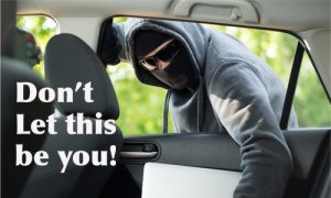 image of a thief breaking into a car and stealing the computer in the back seat