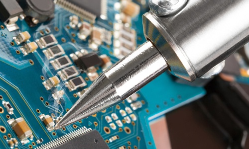 Image of a soldering iron on a computer circuit.